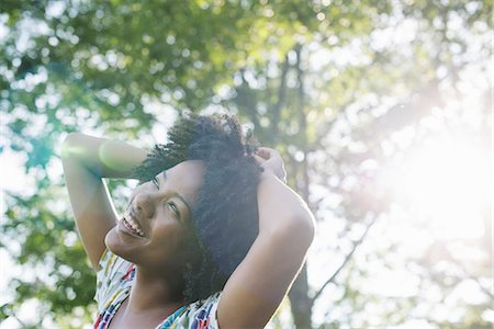 freedom, african american - A young woman in a flowered summer dress with her hands behind her head, smiling and looking up. Stock Photo - Premium Royalty-Free, Code: 6118-07351597