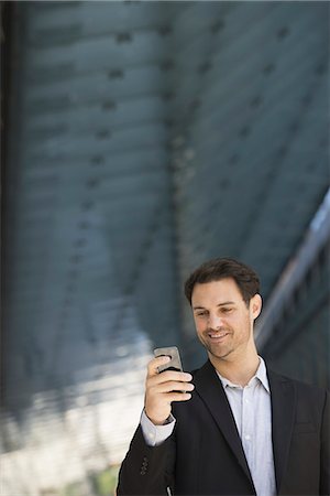 Business people in the city. Keeping in touch on the move. A man in a black jacket and open collared shirt using a smart phone. Foto de stock - Sin royalties Premium, Código: 6118-07351513