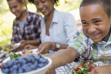 simsearch:6118-07203926,k - A family picnic in a shady woodland. Adults and children sitting at a table. Foto de stock - Sin royalties Premium, Código: 6118-07351531