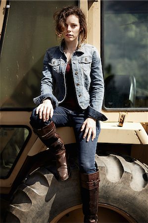 simsearch:6118-07354282,k - A young woman in denim jacket and boots on the hood of a tractor. Stockbilder - Premium RF Lizenzfrei, Bildnummer: 6118-07351637