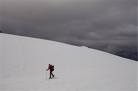 A skier skins or traverses up a snow field as dark clouds gather on Mount Baker, Washington, USA. Foto de stock - Royalty Free Premium, Número: 6118-07351712