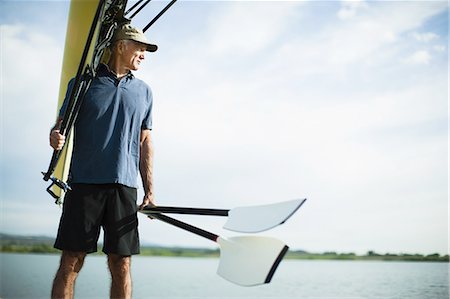 A middle-aged man carrying oars and a rowing shell on his shoulder. Photographie de stock - Premium Libres de Droits, Code: 6118-07351858