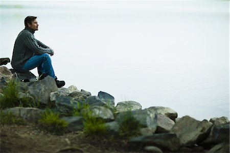 simsearch:6118-07351879,k - A middle-aged man sitting on rocks looking pensively over the water. Stock Photo - Premium Royalty-Free, Code: 6118-07351869