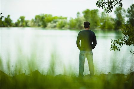 simsearch:6118-07351872,k - A man standing alone looking into the distance across the water, deep in thought. Foto de stock - Royalty Free Premium, Número: 6118-07351872