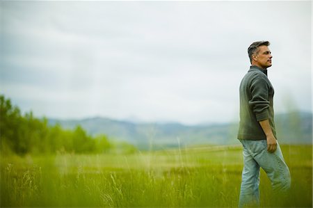 A man standing alone looking into the distance, deep in thought. Stock Photo - Premium Royalty-Free, Code: 6118-07351877
