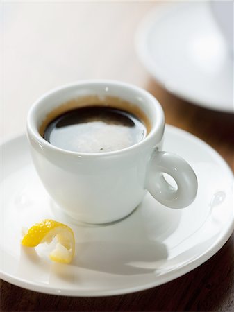 A cup of black coffee in a white china cup with a small twist of lemon peel in the saucer. Stock Photo - Premium Royalty-Free, Code: 6118-07351809