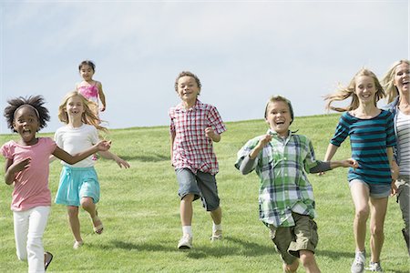 simsearch:640-02951657,k - A group of children running across a grass field. Fotografie stock - Premium Royalty-Free, Codice: 6118-07351833