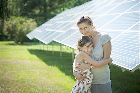 A child and her mother in the fresh open air, beside solar panels on a sunny day at a farm in New York State, USA. Photographie de stock - Premium Libres de Droits, Code: 6118-07351951