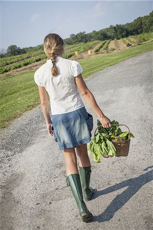 simsearch:6118-07351904,k - A girl in boots carrying a basket full of fresh produce. Stock Photo - Premium Royalty-Free, Code: 6118-07351900