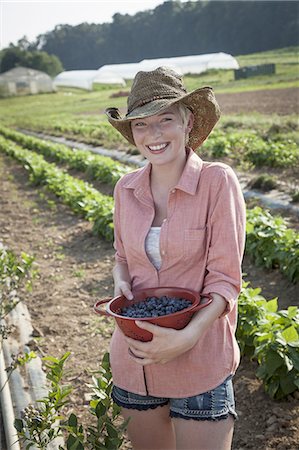 A girl in a pink shirt holding a large bowl of harvested blueberry fruits. Photographie de stock - Premium Libres de Droits, Code: 6118-07351915