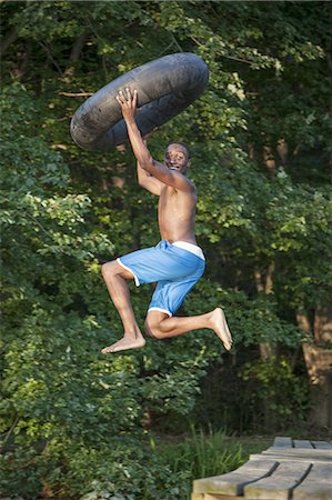 floating dock - A young person, boy holding a swim float tyre over his head and leaping into the water from the jetty. Foto de stock - Sin royalties Premium, Código: 6118-07351930