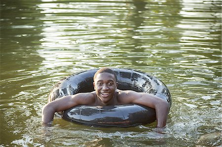 simsearch:6118-07351919,k - A boy floating in the water using a tyre swim float. Foto de stock - Sin royalties Premium, Código: 6118-07351934
