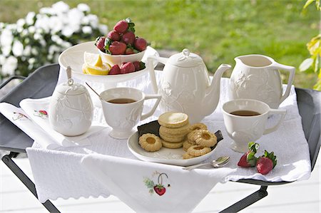 simsearch:669-07161792,k - A traditional afternoon tea set out on a tea tray in a garden with white china and strawberries. Foto de stock - Sin royalties Premium, Código: 6118-07352007