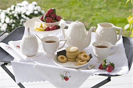 simsearch:6118-07354051,k - A traditional afternoon tea set out on a tea tray in a garden with white china and strawberries. Foto de stock - Sin royalties Premium, Código: 6118-07352007