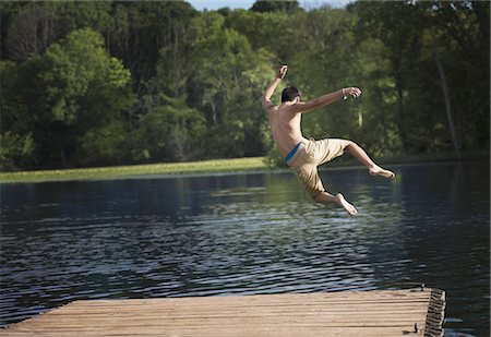 simsearch:6118-07769586,k - A boy taking a running jump into a calm pool of water, from a wooden jetty. Foto de stock - Sin royalties Premium, Código: 6118-07352023