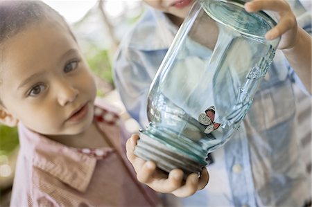 A child holding a glass jar and examining a butterfly. Stock Photo - Premium Royalty-Free, Code: 6118-07352170