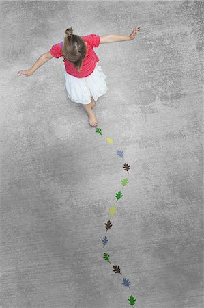 View from overhead of a child creating and walking along a line of coloured leaf shapes. Photographie de stock - Premium Libres de Droits, Code: 6118-07352197