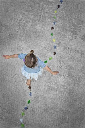 View from overhead of a child creating and walking along a line of coloured leaf shapes. Photographie de stock - Premium Libres de Droits, Code: 6118-07352196