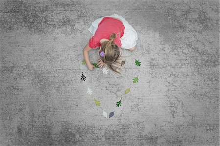 simsearch:6118-07352198,k - View from overhead of a child creating and walking along a line of coloured leaf shapes. Stock Photo - Premium Royalty-Free, Code: 6118-07352198