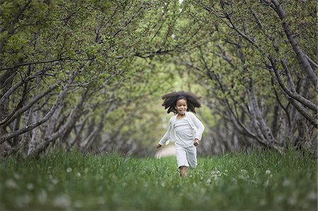 environmental conservation - A child running along a natural woodland tunnel with tree branches forming an arch. Stock Photo - Premium Royalty-Free, Code: 6118-07352206