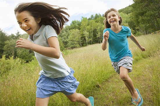 Two children, girls running and playing chase, laughing in the fresh air. Stock Photo - Premium Royalty-Free, Image code: 6118-07352381