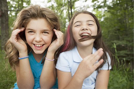 Two girls, friends sitting side by side, playing and laughing. Photographie de stock - Premium Libres de Droits, Code: 6118-07352388