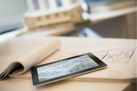 An architectural practice office. A desktop with blueprints and architectural plans, and a computer tablet. Architect's model of a house. Photographie de stock - Premium Libres de Droits, Code: 6118-07352600