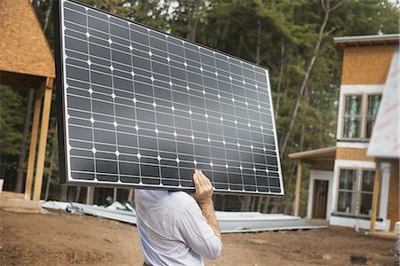 solar panel house - A workman carrying a large solar panel at a green house construction site. Stock Photo - Premium Royalty-Free, Code: 6118-07352613