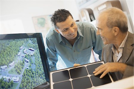 simsearch:6118-07352604,k - Two men in an architecture office. Working on a green construction project, sitting by a screen. A man holding a tile sample. Fotografie stock - Premium Royalty-Free, Codice: 6118-07352611