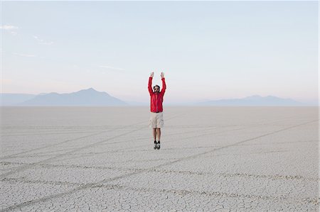 simsearch:6118-07354266,k - A man jumping in the air on the flat desert or playa or Black Rock Desert, Nevada. Photographie de stock - Premium Libres de Droits, Code: 6118-07352749