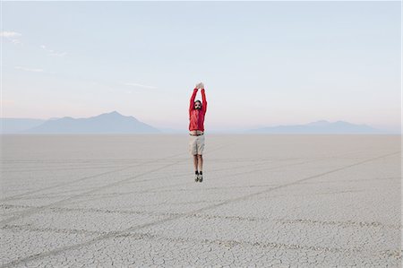 simsearch:6118-07731759,k - A man jumping in the air on the flat desert or playa or Black Rock Desert, Nevada. Foto de stock - Royalty Free Premium, Número: 6118-07352750