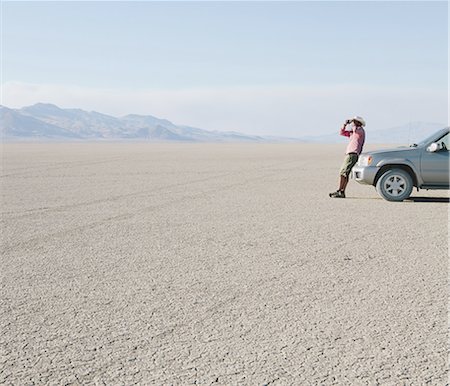 salt plains - A man leaning against a truck, looking through binoculars. Photographie de stock - Premium Libres de Droits, Code: 6118-07352763