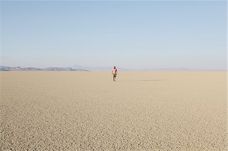 Man walking across a flat desert landscape Photographie de stock - Premium Libres de Droits, Code: 6118-07352764