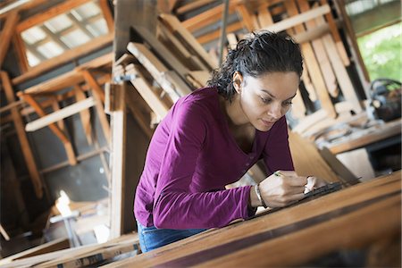 simsearch:6118-07353418,k - A woman working with reclaimed timber in a woodwork workshop. Foto de stock - Royalty Free Premium, Número: 6118-07352816