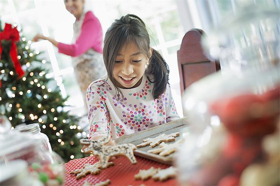 A young girl decorating Christmas cookies with icing. Stock Photo - Premium Royalty-Free, Image code: 6118-07352962