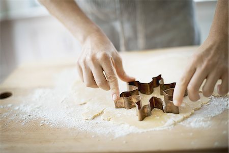 Woman making organic Christmas cookies, cutting dough with a cookie cutter. Stock Photo - Premium Royalty-Free, Code: 6118-07352976