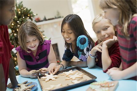 A group of children around a table, decorating organic Christmas cookies. Photographie de stock - Premium Libres de Droits, Code: 6118-07352998