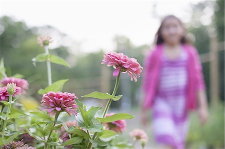 simsearch:633-06322693,k - A young girl in a pink dress, walking past a bed of flowers in an organic garden. Stock Photo - Premium Royalty-Free, Code: 6118-07353032