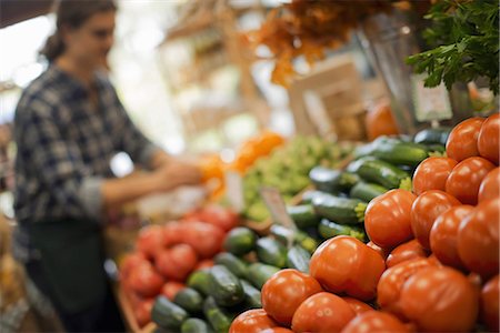 fresh produce - Organic Farmer at Work. A young man arranging a display of fresh produce on a farm stand, tomatoes and cucumbers. Photographie de stock - Premium Libres de Droits, Code: 6118-07353343