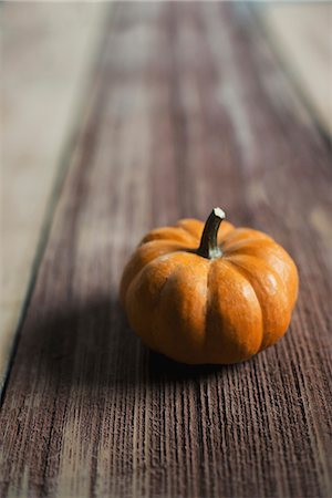 simsearch:6118-07353360,k - A small round pumpkin or squash vegetable with a bright orange skin, on a wooden tabletop. Stock Photo - Premium Royalty-Free, Code: 6118-07353355