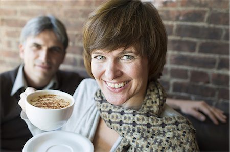 Two people sitting in a coffee shop. A man and woman, holding white china cups of cappuccino coffee. Photographie de stock - Premium Libres de Droits, Code: 6118-07353461