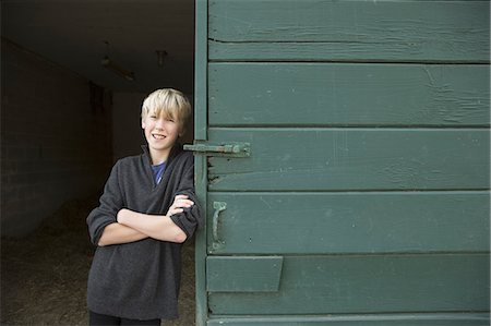 simsearch:6118-07439819,k - A boy leaning against a wooden barn door, at an animal sanctuary. Stock Photo - Premium Royalty-Free, Code: 6118-07353477