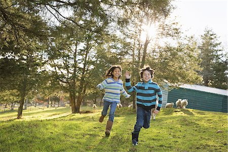 simsearch:6118-07439819,k - Two children at an animal sanctuary, in a paddock feeding two sheep. Stock Photo - Premium Royalty-Free, Code: 6118-07353475