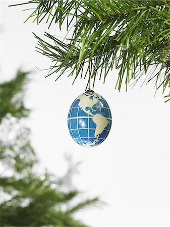 Still life. Green leaf foliage and decorations. A pine tree branch and a blue and white bauble. A globe with continents outlined on a blue background. Stock Photo - Premium Royalty-Free, Code: 6118-07353486
