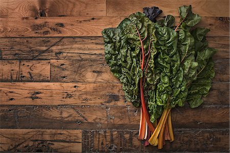 A group of red and orange chard leaves with bright coloured stems. Organic vegetables, frehsly picked, and placed on a wooden board. Stock Photo - Premium Royalty-Free, Code: 6118-07353434