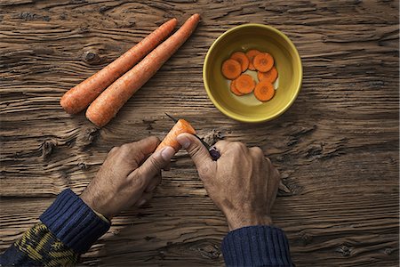 simsearch:6118-07353427,k - A person holding and slicing fresh carrots into a bowl. Foto de stock - Sin royalties Premium, Código: 6118-07353438