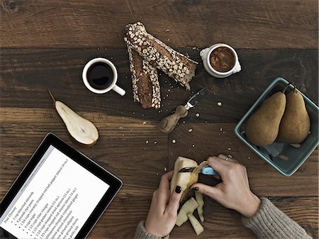 food top view - A person using a peeling knife to peel a pear. A computer tablet device with the screen displaying instructions, a recipe. Stock Photo - Premium Royalty-Free, Code: 6118-07353506