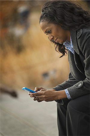 City life. A woman in a coat, checking and texting, keeping in contact, using a mobile phone. Photographie de stock - Premium Libres de Droits, Code: 6118-07353685