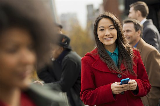 City life. A group of people on the go, keeping in contact, using mobile phones, and talking to each other. Two women and two men. Stock Photo - Premium Royalty-Free, Image code: 6118-07353697