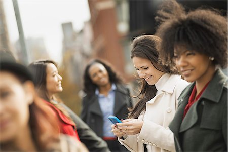 City life. A group of people on the go, keeping in contact, using mobile phones, and talking to each other. Five women. Stock Photo - Premium Royalty-Free, Code: 6118-07353695